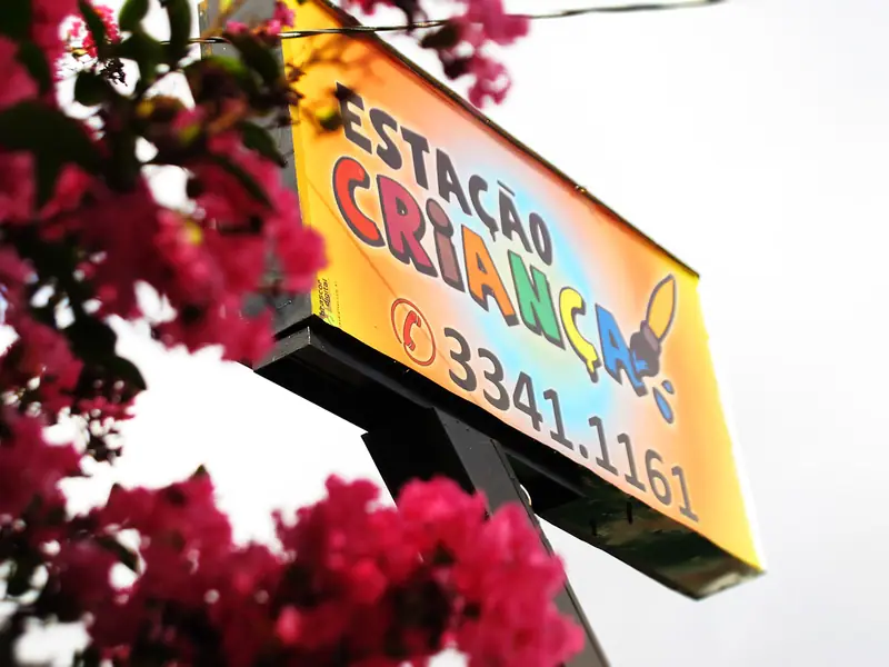 Placa da Estação Criança entre os galhos de uma árvore florida